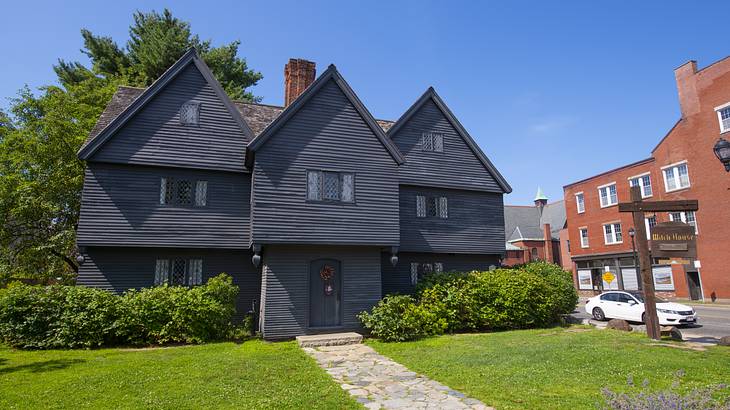 A walkway between green grass to a black vernacular house A walkway between green grass to a black vernacular house