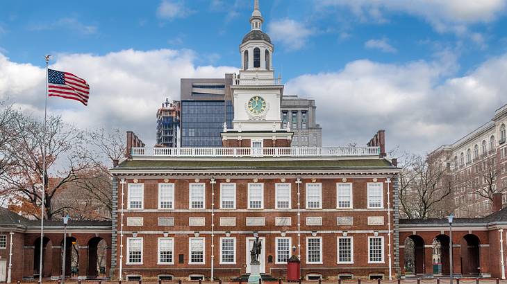 An American flag outside a red brick building with a clock tower An American flag outside a red brick building with a clock tower