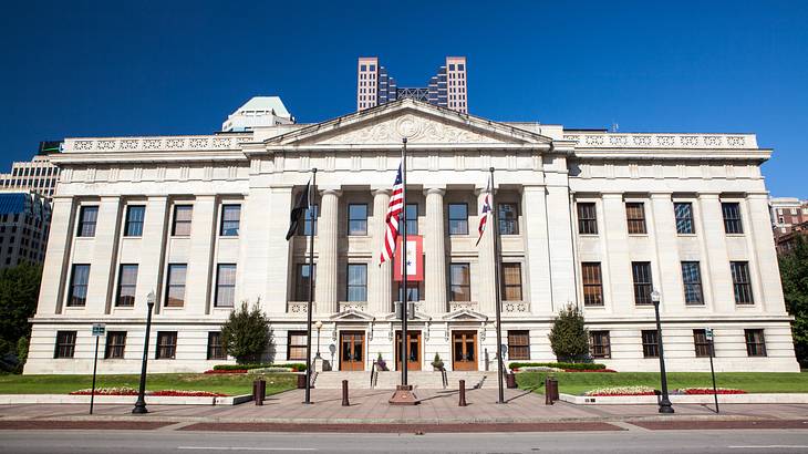 Three flags in front of a white Greek Revival building with four columns Three flags in front of a white Greek Revival building with four columns