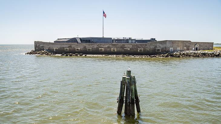 A walled sea fort on an island displaying the American flag