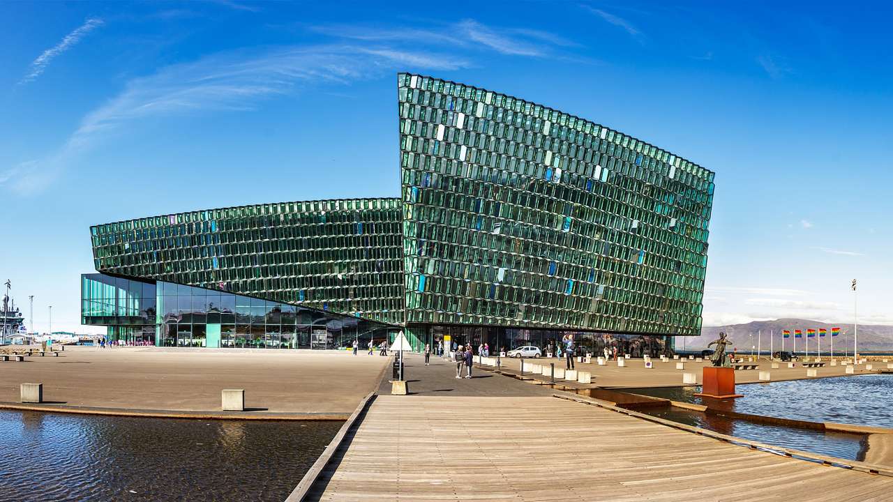 A modern glass structure with a wooden boardwalk surrounded by water
