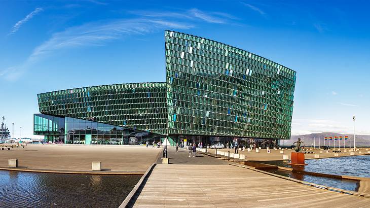 A modern glass structure with a wooden boardwalk surrounded by water