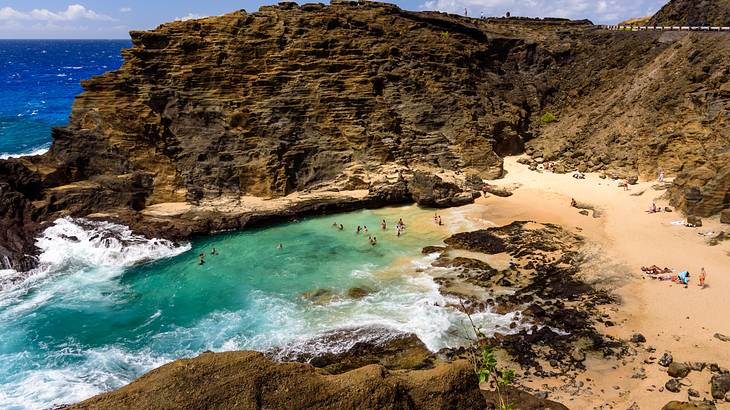 Tall rocky cliffs form a bay filled with turquoise water and a yellow sandy beach