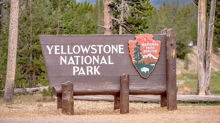 Wood "Yellowstone National Park" sign an orange emblem with mountains and trees
