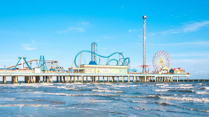 Fair rides on a coastal pier with ocean water surrounding it