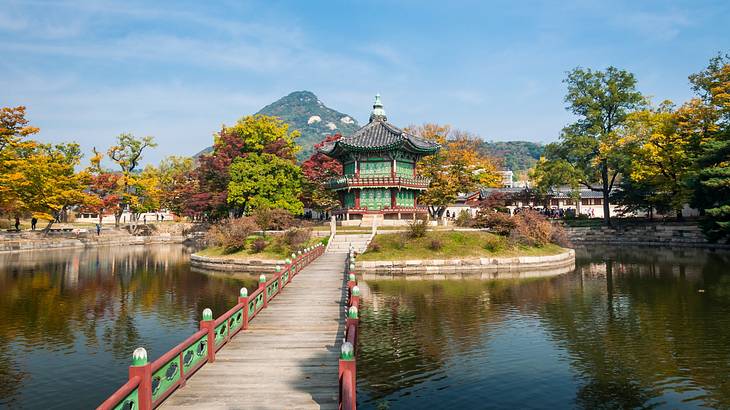 An Asian pagoda-style structure next to a path and surrounded by trees and water