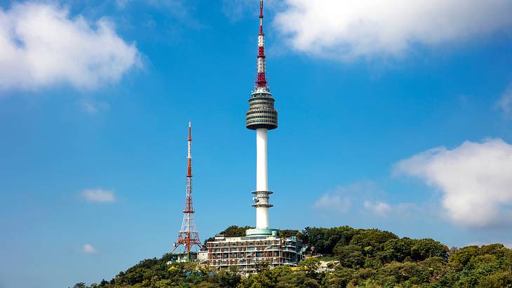 A tower next to a smaller structure on a greenery-covered hill