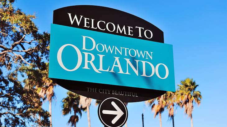 A blue sign "Welcome to Downtown Orlando" with palm trees in the background