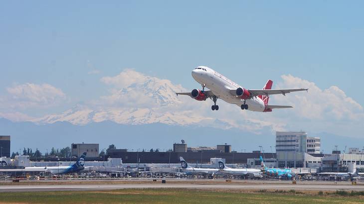 An airplane taking off from an airport runway with snowy mountains behind it
