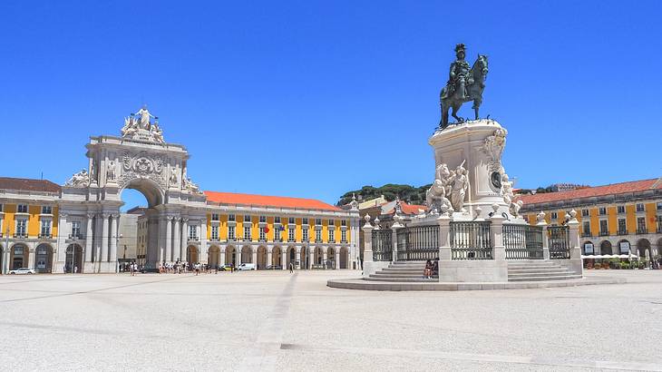 A stone arch and a statue of a horse on a square