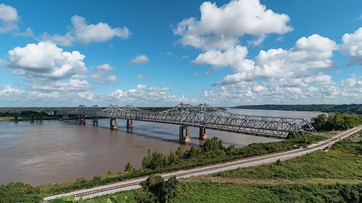 A steel bridge connecting 2 sides of a river during daytime A steel bridge connecting 2 sides of a river during daytime