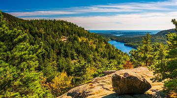 A rocky cliff with trees overlooking a body of water