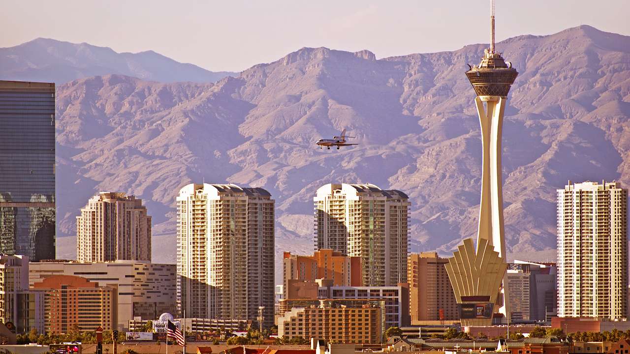 A plane flying over buildings with mountains in the distance