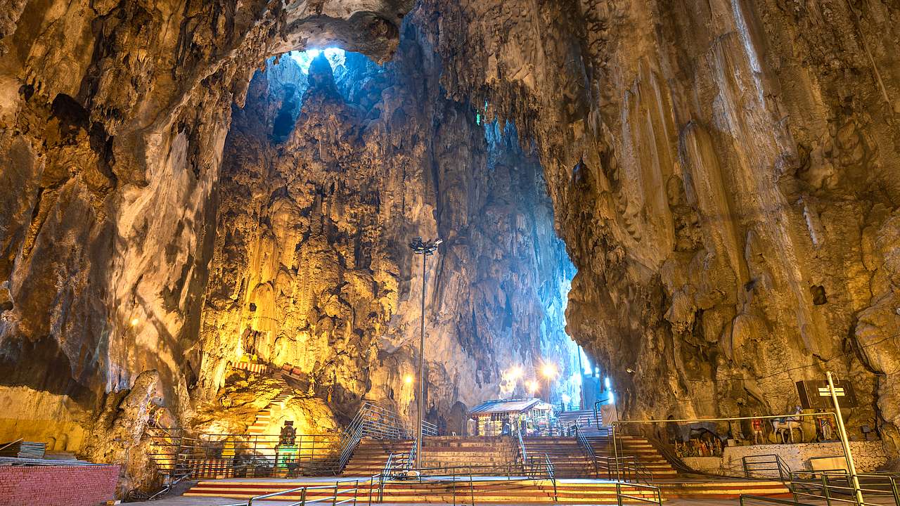 A shrine situated in a large cave with lighting and a paved floor and steps