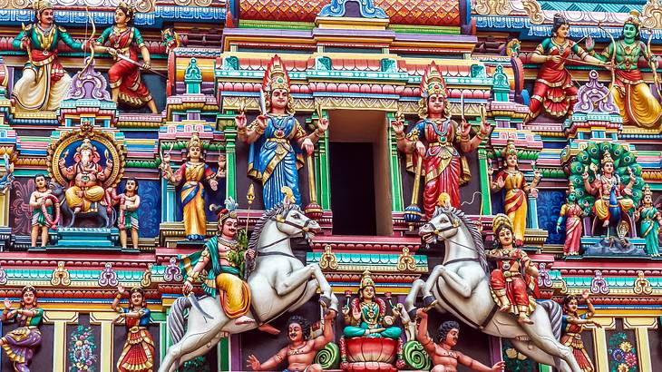 A close-up of many colorful, carved Hindu figures on the facade of a temple