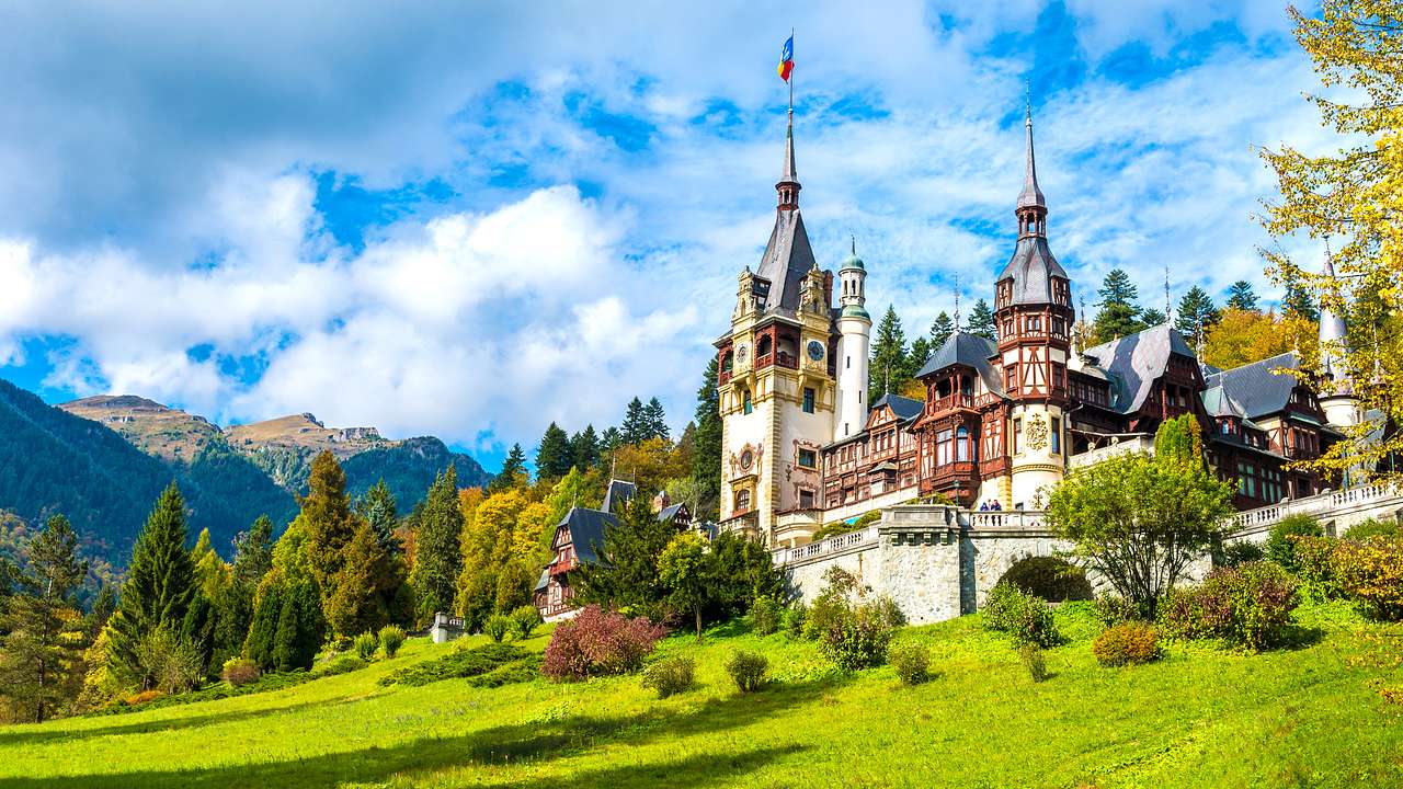 Panorama of a royal castle amongst trees and mountains in Sinaia, Romania