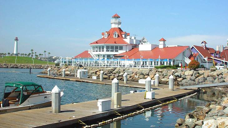 A walkway over a body of water leading to a red-roofed gazebo-type building