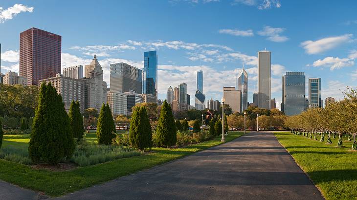 An urban park with greenery, a path, and skyscrapers in the background