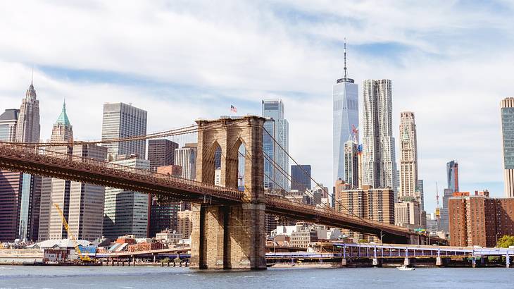 A suspension bridge over water next to a city skyline