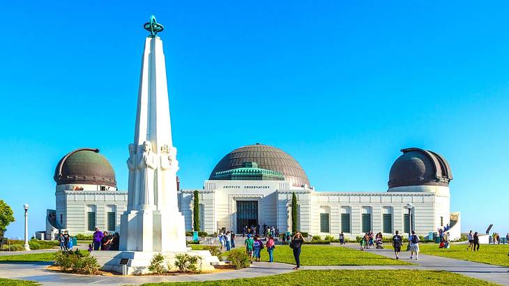 A white observatory building with green grass in front of it under a blue sky