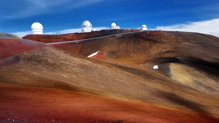 Four white structures with domes atop a hilly barren mountain Four white structures with domes atop a hilly barren mountain