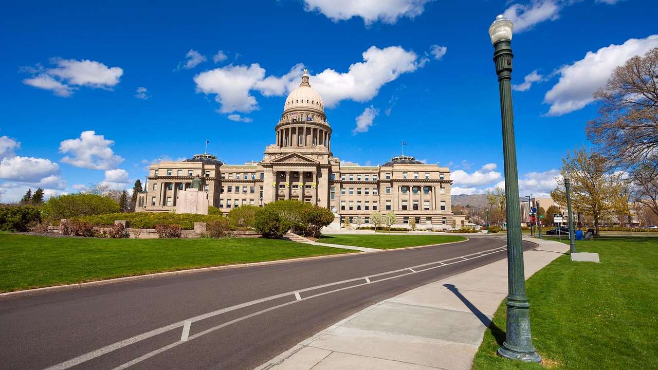 A road between green grass, leading to a neoclassical capitol building