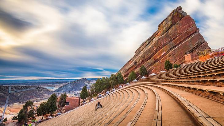 Steps carved into red rock with a mountain peak to the side under a cloudy sky