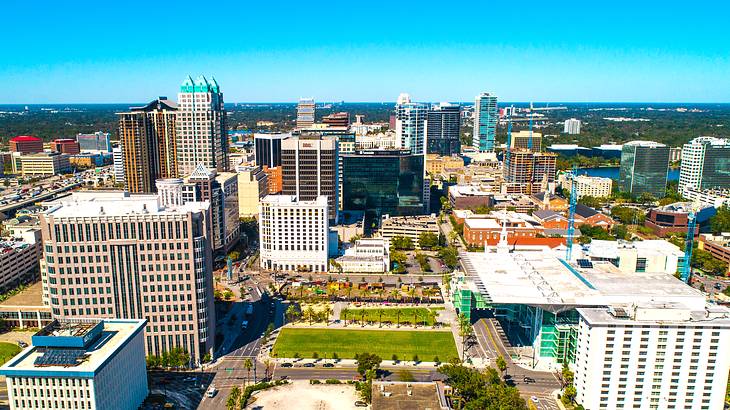 Aerial view of a city with tall and low buildings and a green field in the middle