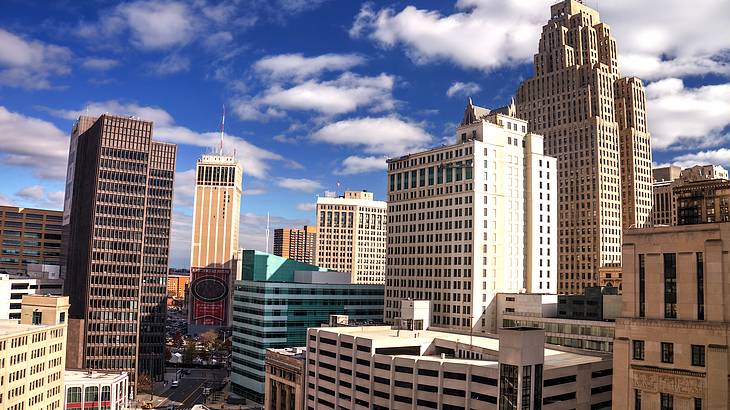 A cityscape of tall buildings towering over a street in the middle on a sunny day