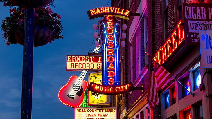 Neon lights and signs against buildings, one saying "Nashville Crossroads Music City" Neon lights and signs against buildings, one saying "Nashville Crossroads Music City"