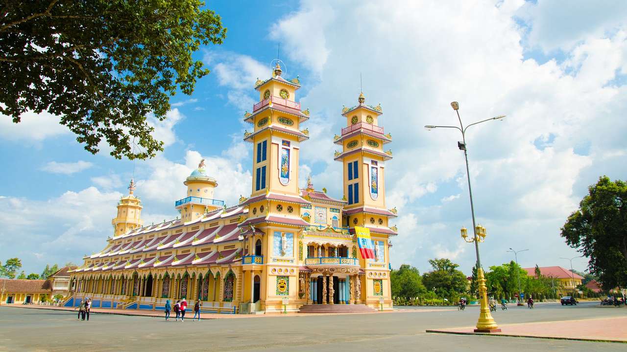 A temple with two towers next to a road and trees