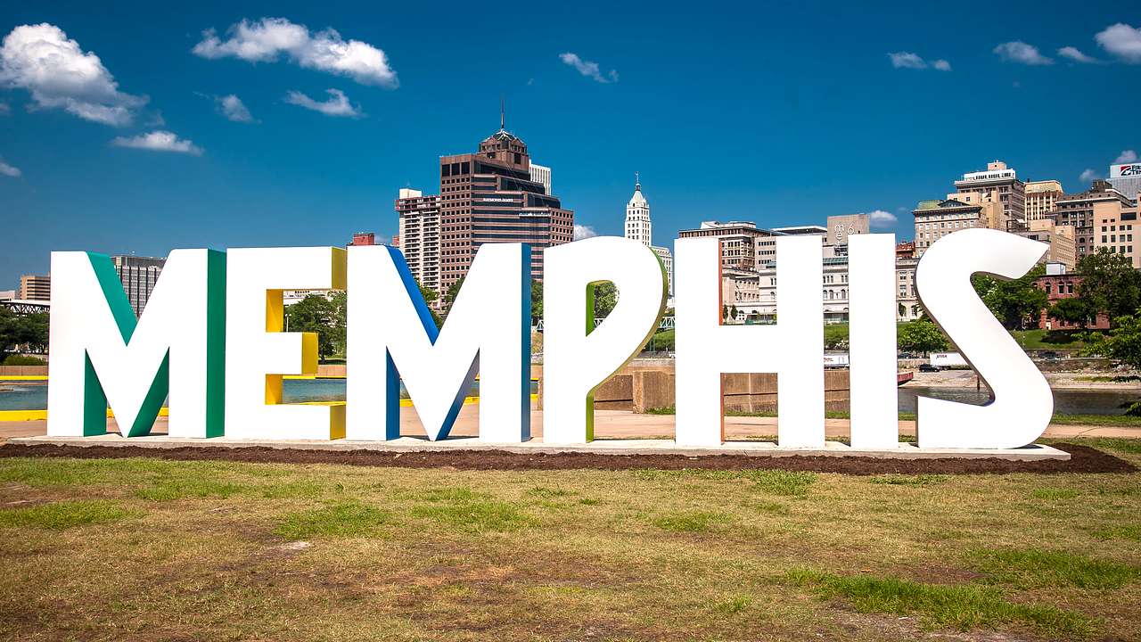 A large white sign on a grassy lawn that says "Memphis," with buildings behind it