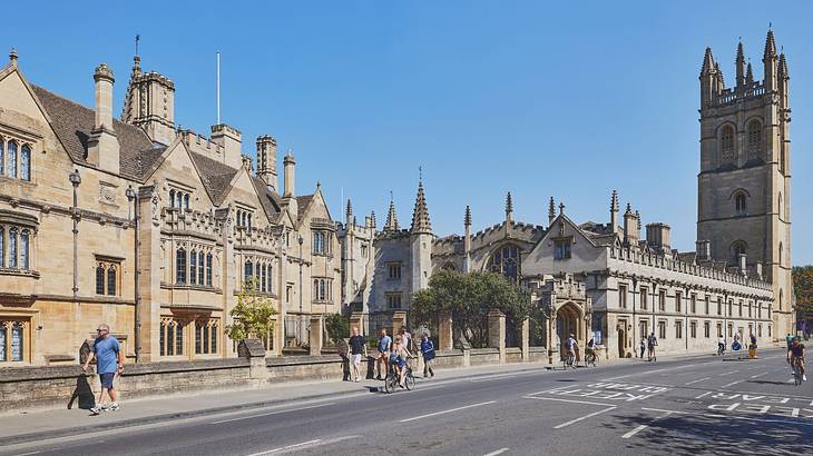 A stone building next to a church tower and a road under a blue sky