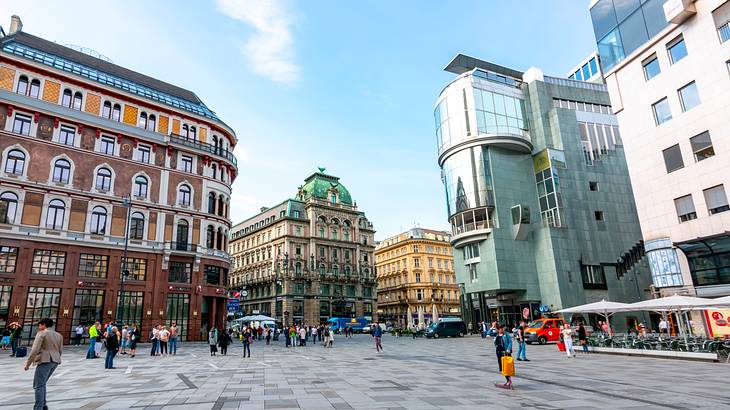 A busy square filled with modern and historic buildings with people walking around