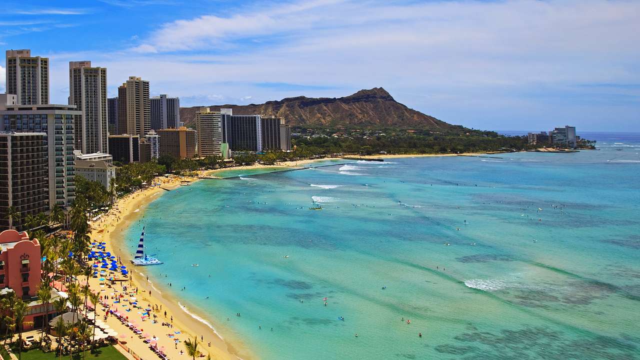 A beach with skyscrapers to the side and a mountain in the background