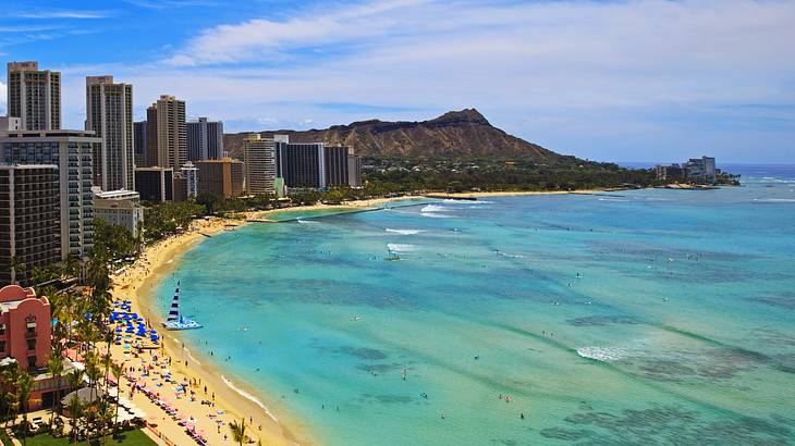 A beach with skyscrapers to the side and a mountain in the background