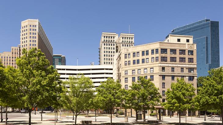 Tall buildings with a park in front under a blue sky