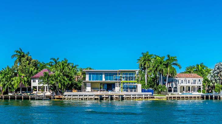 Beach houses and palm trees next to the blue water under a blue sky