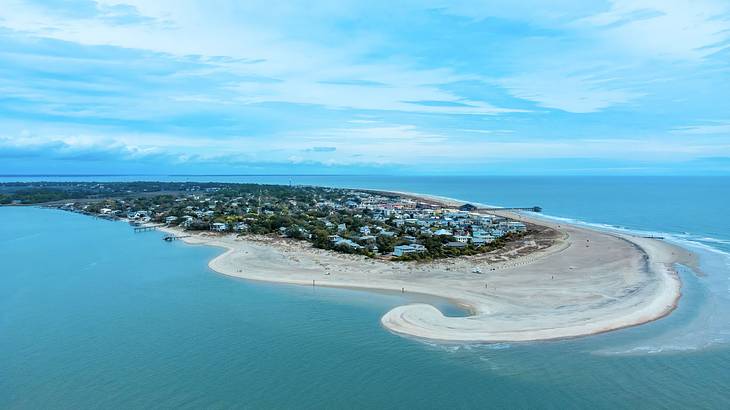 An aerial view of an island with trees and houses under a partly cloudy sky