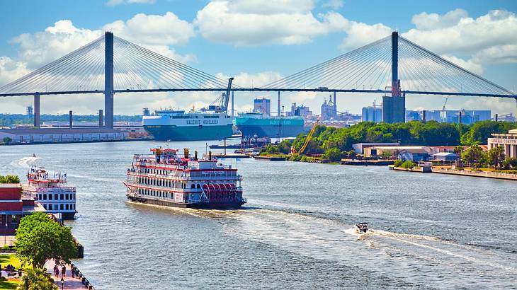 A body of water with ships, boats, and a bridge across it, surrounded by buildings