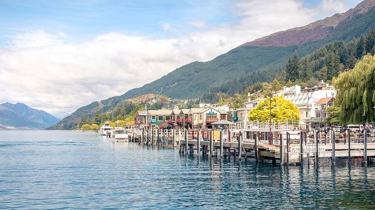 A town located beside a lake and mountains on a cloudy day