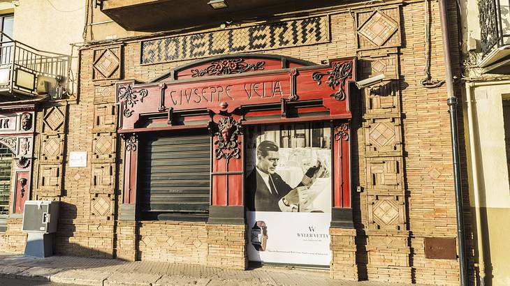 An old-fashioned building with red details and a black and white image of a man on it