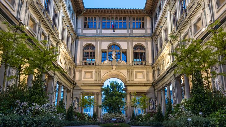 A structure adorned with columns and glass windows, surrounded by green plants