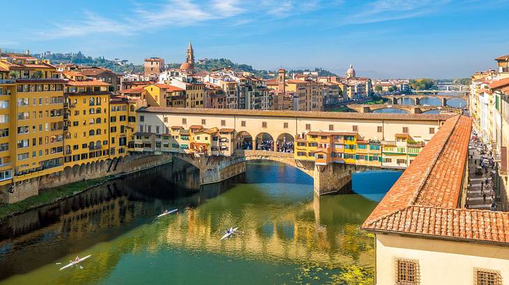 A bridge over a river with buildings surrounding it under a blue sky