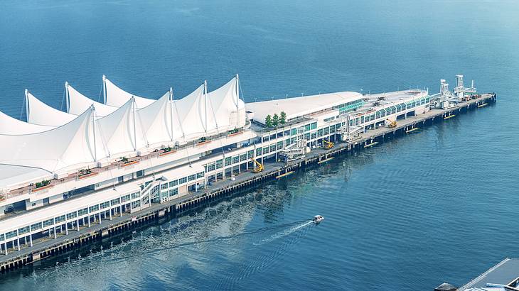 An aerial shot of a white sailboat-like building surrounded by water