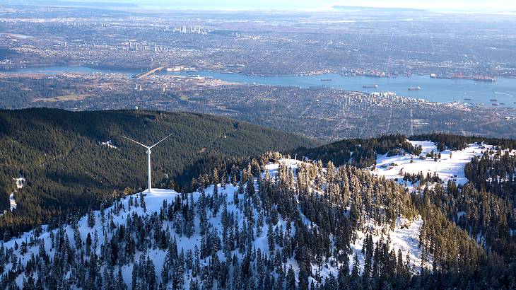 Aerial view of a mountain covered in snow with trees overlooking a city