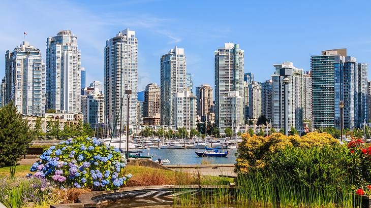 A garden with colorful flowers in front of a harbor with boats and buildings