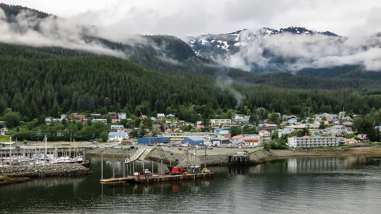 A coastal town at the foot of snowy mountains on a foggy day