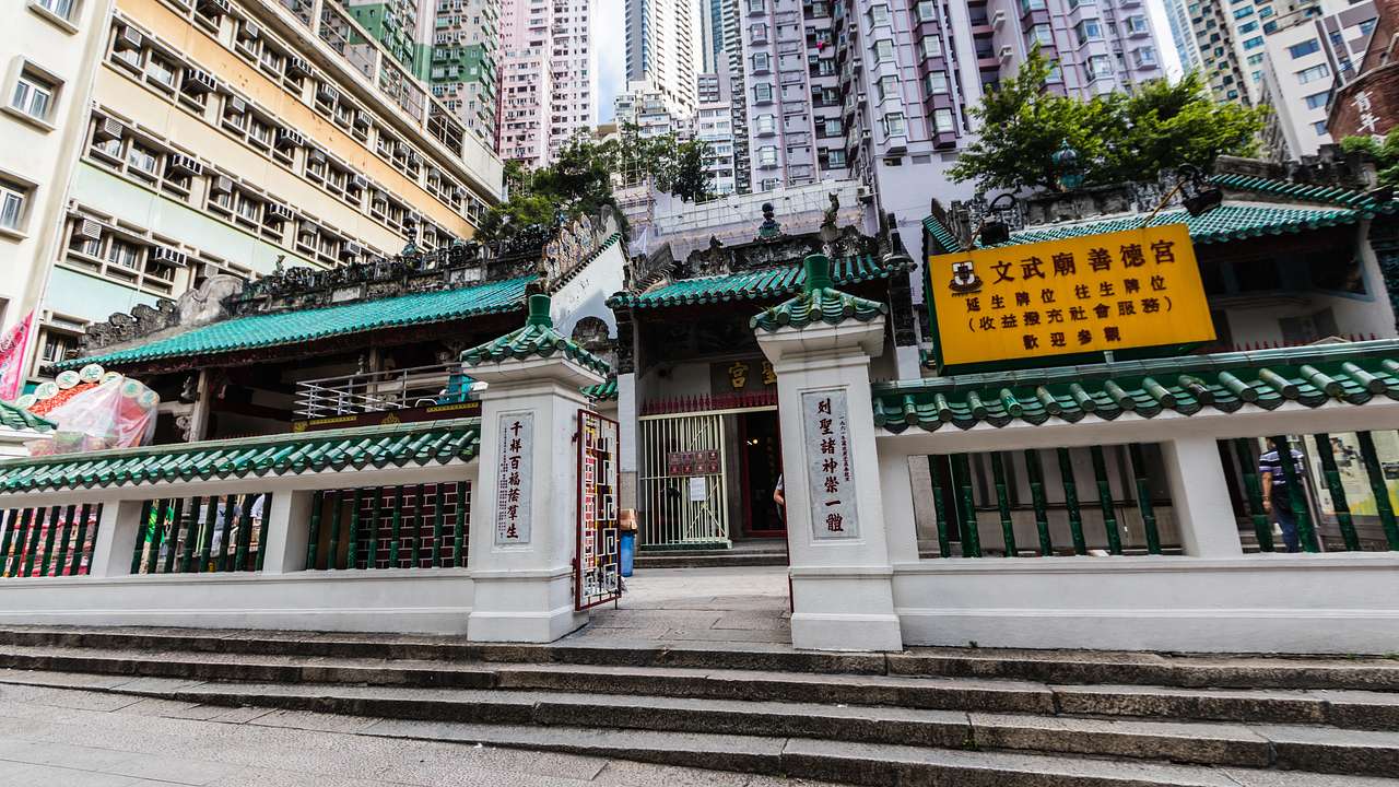 A white and green temple with signs on it next to high-rise buildings