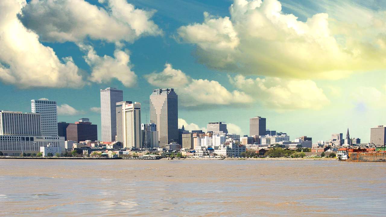 A river with a city skyline in the distance under a cloudy sky